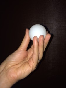 A hand holding a ping pong ball